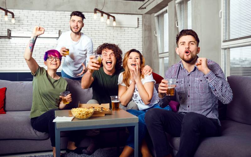 Group of LGBTQ+ friends watching Eurovision show and cheering